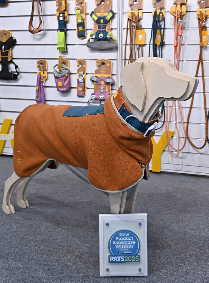 Figure 10. Award-winning dog wear on display at PATS 2025 — a fleece coat on a plywood dog mannequin with a New Product Showcase Winner placard. Field photo from the author's on-site collection, PATS 2025.