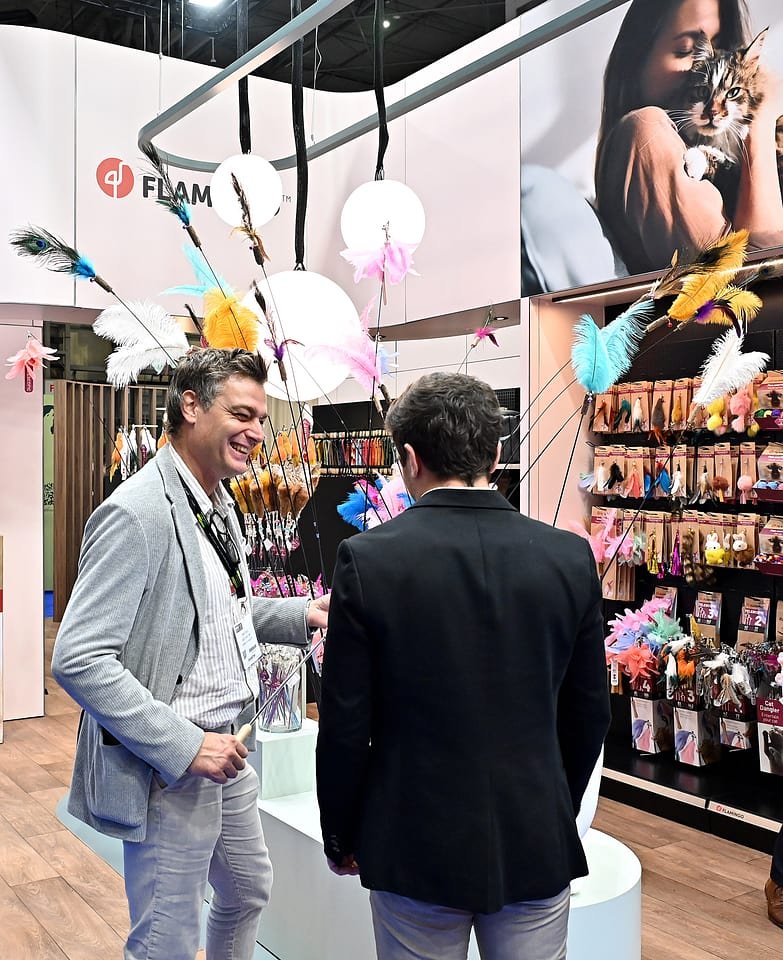 Figure 17. Flamingo's cat toy stand at PATS 2025 — feather teaser wands and packaged toys merchandised for maximum visual impact. Field photo from the author's on-site collection, PATS 2025.
