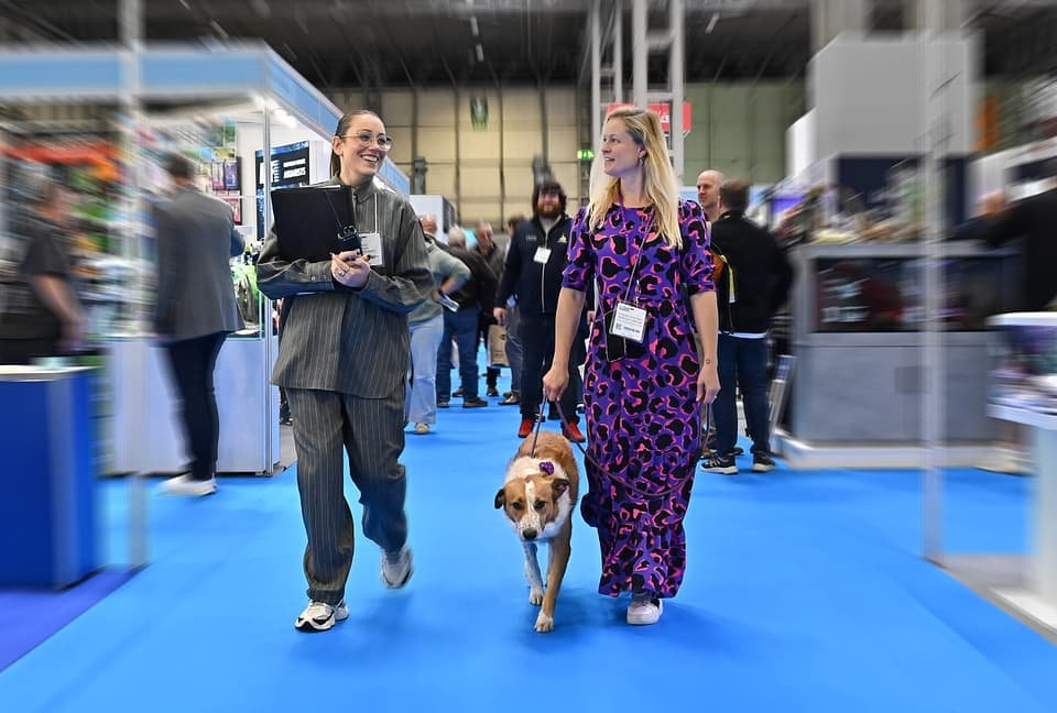 Figure 11. A typical PATS 2025 aisle scene — visitors, a trade dog and the hall's blue carpet, with "AQUARISTS" signage ahead. Field photo from the author's on-site collection, PATS 2025.